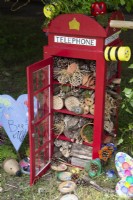 An insect hotel made by children from a model red telephone box