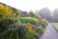 Aster 'Harrington's Pink, Aster frikatii 'Monch', Soligado canedensis, Eupatorium purpurea and Rudbeckia in the Long Border at Waterperry Gardens.