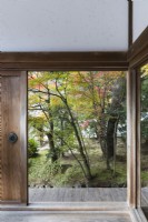 View into the Landscaped garden through frame of temple building. Acers in autumn colour.