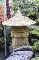 Fragile stone ornament wrapped in decorative straw covering to prevent frost damage. 