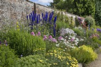 Mixed border against a brick wall at Waterperry Gardens, July