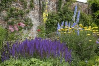 Mixed border against a brick wall at Waterperry Gardens, July