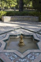 Low and tiled fountains in a Moorish style are found all over the Real Alcazar Palace gardens, Seville. Spain. September. 