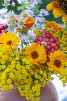 Bouquet with pot marigold, nasturtium, guelder rose berries, tansy and tall fleabane in a honey clay pot.