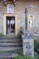 Entrance to the Cloisters framed by various sculptures including thirteenth century Lombardic lions at Iford Manor