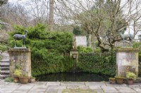Semi-circular pool with river god and framed by deer on plinths at Iford Manor in January