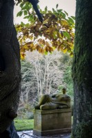 Castanea sativa, sweet chestnut in autumn, with Henry Moore's sculpture 'Memorial Figure' beneath