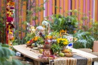 Garden table decorated of Indian ornaments, colourful flowers, fruits and spices in The RHS and Eastern Eye Garden of Unity, designer: Manoj Malde