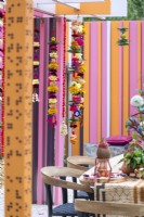 Marigold garlands made of flowers, chilli peppers and fruits used as decorations for dining area. The RHS and Eastern Eye Garden of Unity, Designer: Manoj Malde