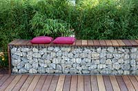 Gabion as a seating area in front of a bamboo hedge 