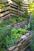 Plant beds made of old stones, fence made of bark boards 