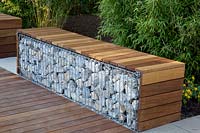 Gabion as a seating area in front of a bamboo hedge 