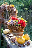 Bouquet of flowers in a vase wrapped with oak leaves, Quercus rubra, Dahlia, Aster, Calendula, Malus, Cucurbita pepo 