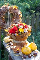 Bouquet of flowers in a vase wrapped with oak leaves, Quercus rubra, Dahlia, Aster, Calendula, Malus, Cucurbita pepo 