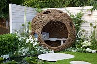 Willow arbor in a small garden with pond and chamomile as a lawn substitute 