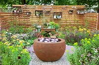 Small garden with water bowl, planting table and shelves on a wooden wall 