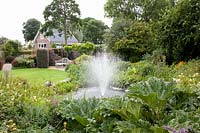 Pond with fountain in the country house garden, Gunnera 