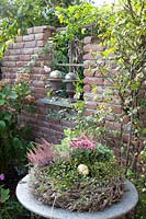 Ruined wall in the garden and autumn wreath on a table 