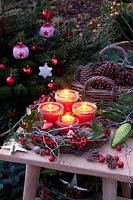 Advent wreath with candles in jars on a tray, decorated with moss, holly branches and cones 