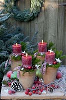 Candles in pots, decorated with moss and ribbon 