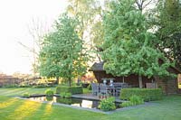 Seating area at the formal water basin with Chinese ornamental pear, Pyrus calleryana Chanticleer 