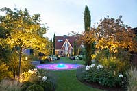 Illuminated garden with pool, serviceberry and crabapple, Amelanchier, Malus 
