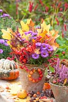 Autumnal arrangement with foliage, ornamental apple, heather, spindle tree and Aster dumosus Purple Dome 