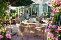 Seating area between potted plants, Mandevilla, Pelargonium 