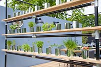Shelf on modern terrace with herbs in recycled cans 