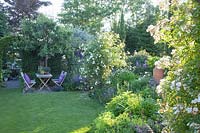 Country house garden with seating area under pear tree 
