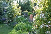 Perennial bed with roses and amphora 