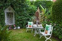 Seating area in the garden with Cordyline australis in a pot 