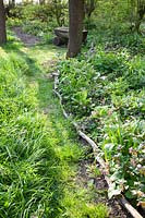 Path in the natural garden with bed edging made of branches 