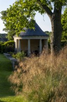 Temple style summerhouse in summer garden with Stipa gigantea, Giant Oat Grass