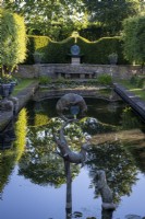 Ornamental sculptures of otters by Susie Wilson frolic above a formal pond which mirrors the surrounding formal garden.