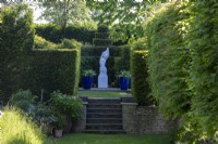 Classical statue of a woman undressing, surrounded by topiary hedging of Hornbeam and Yew.