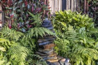 Slate water fountain surrounded by fern leaves