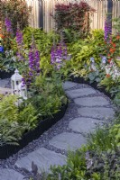 A stone and gravel path surrounded by beds planted with Digitalis purpurea, ferns and hostas. Designer: Darragh Collopy, Bord Bia Bloom 2023 
