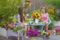 The girls hang out drinking and reading magazines on the terrace.