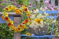 Basket with picked chamomile and sunflowers and summer flower wreath made of Helianthus, Coreopsis, Calendula, Foeniculum and Achillea.