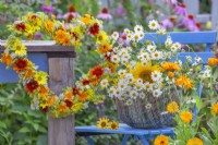 Basket with picked chamomile and sunflowers and summer flower wreath made of Helianthus, Coreopsis, Calendula, Foeniculum and Achillea.