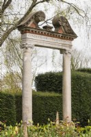 The Triumphal Arch with lettering in Latin. Yew hedges. April. Spring.