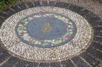 Mosaic in pebbles and glazed tiles with initials. April. Spring.