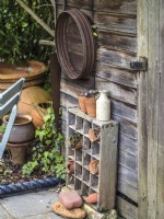 Garden shed with a collection of old gardening tools and display of terracotta pots planted with small succulents