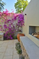 A corner in the patio with blooming Bougainvillea spectabilis climbing of the wall and fireplace in the Mediterranean garden. June
Designer: Alan Rudden
