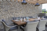 Outdoor dining area under a wooden pergola with Cotswold stone boundary wall - 'The Cotswold Garden' - designer Mark Draper Graduate Gardeners - RHS Malvern Spring Festival 2024