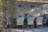 Outdoor dining area on a Yorkstone terrace with Cotswold stone wall and wooden pergola on The Cotswold Garden - designer Mark Draper Graduate Gardeners - RHS Malvern Spring Festival 2024