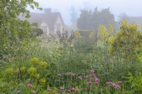 View of mixed annuals and perennials flowering in an informal country cottage garden in early Summer - May